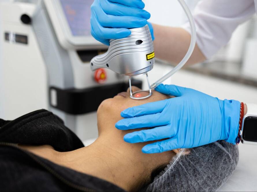 A professional is performing laser treatments on a woman's face.