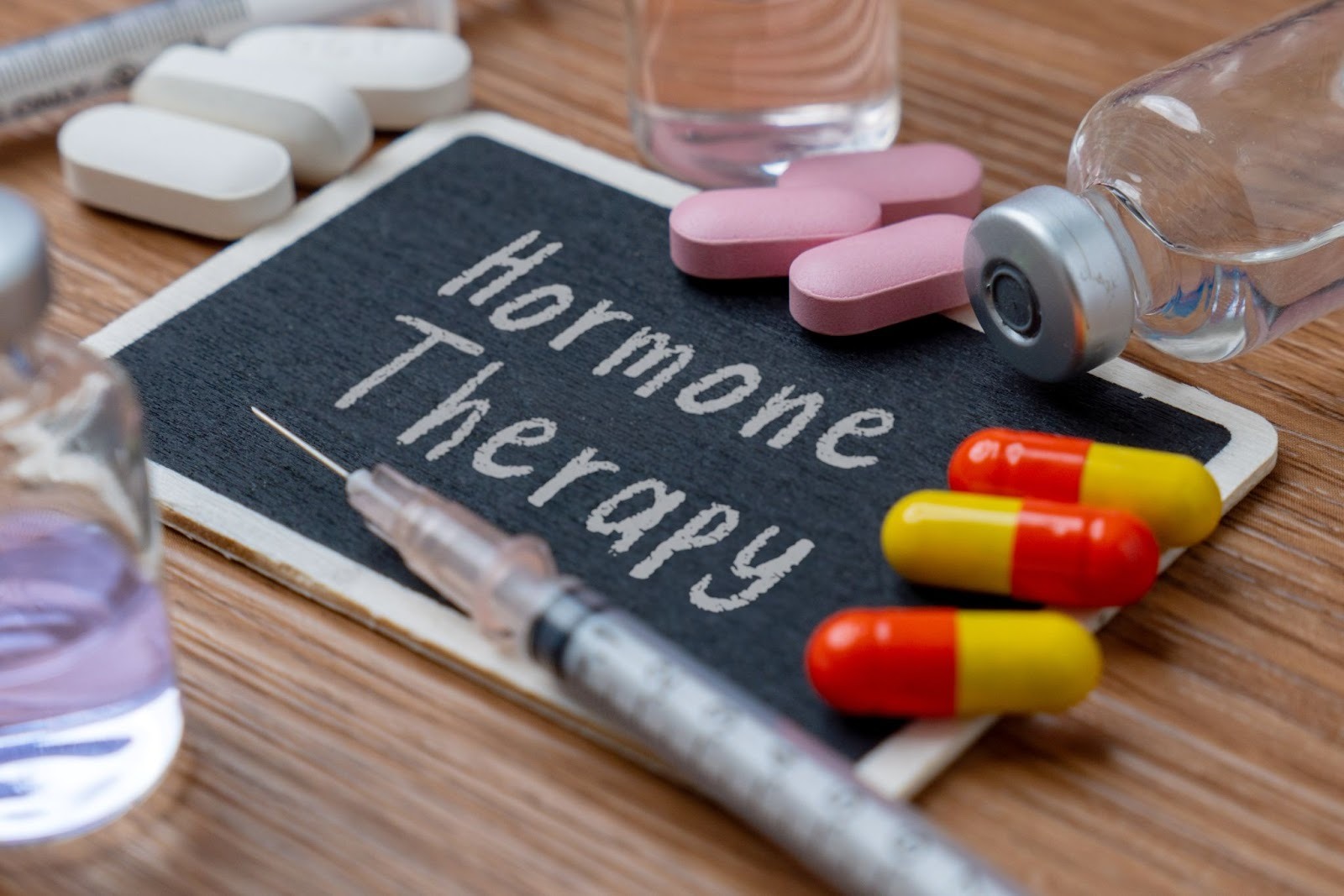 Hormone therapy is written on a chalk board with medications surrounding it.