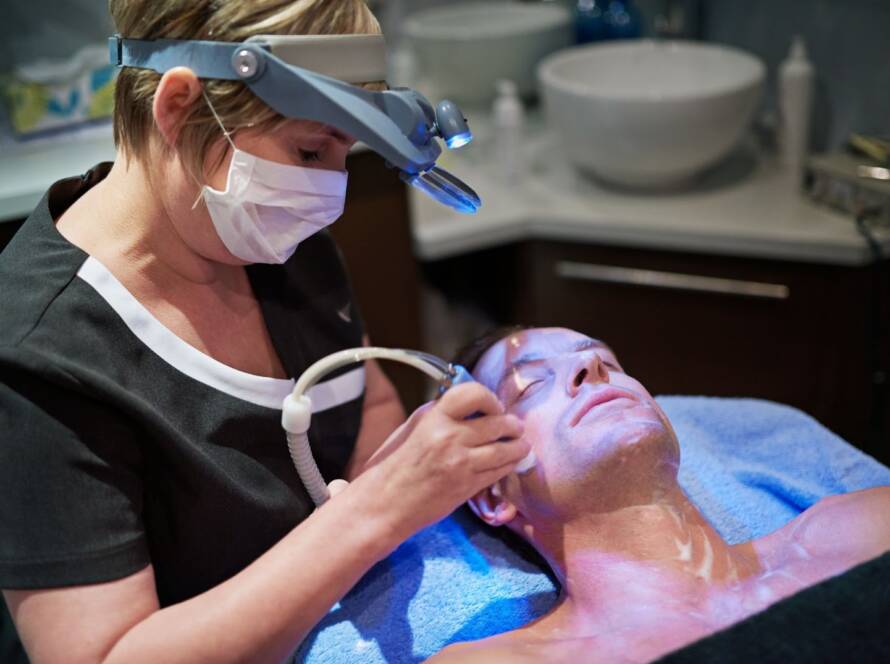 Aesthetician performing radiofrequency treatment on a man during a professional skincare session