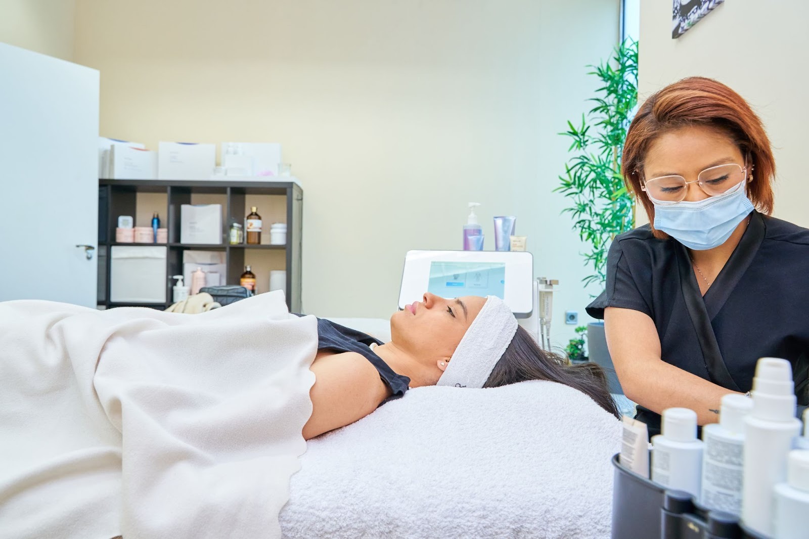 An esthetician prepares a client for a facial cleansing treatment in a medical spa