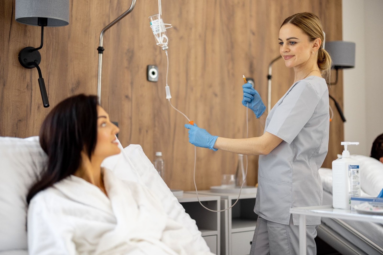 Licensed nurse preparing infusion therapy for a female patient in a clinical wellness setting